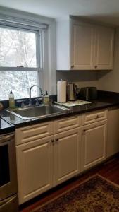 a kitchen with white cabinets and a sink and a window at Charming Townhouse in Historic Town near Boston. in Dedham