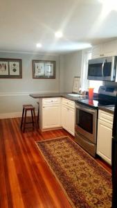 a kitchen with white cabinets and a stove top oven at Charming Townhouse in Historic Town near Boston. in Dedham