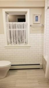 a white bathroom with a toilet and a window at Charming Townhouse in Historic Town near Boston. in Dedham
