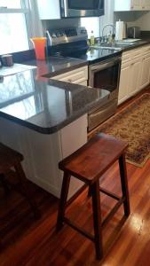 a kitchen with a black counter top and a wooden stool at Charming Townhouse in Historic Town near Boston. in Dedham