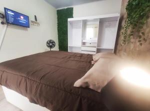 a bedroom with a bed and a tv on a wall at Kitnet Lua - Mobiliada in Belo Horizonte