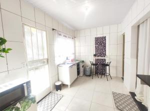 uma cozinha com paredes de azulejos brancos e uma mesa e cadeiras em Kitnet Lua - Mobiliada em Belo Horizonte