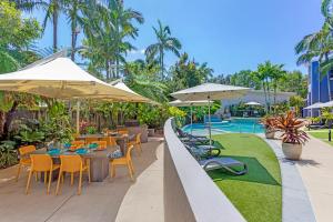 an outdoor dining area with tables and chairs and umbrellas at Verano Resort Noosa in Noosaville