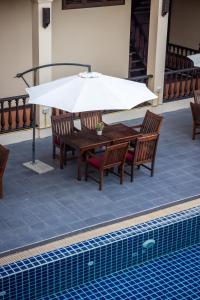 una mesa con sillas y una sombrilla junto a la piscina en Sada Hotel, en Luang Prabang