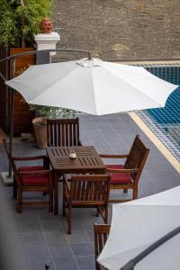 a table and chairs with an umbrella on a patio at Sada Hotel in Luang Prabang