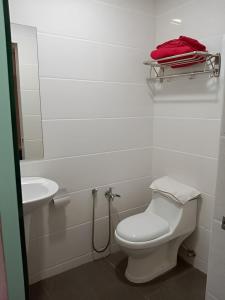 a white bathroom with a toilet and a sink at Hype Motorsport Hotel Nilai in Nilai