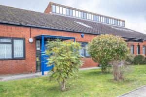 a brick house with a blue door in a yard at Infra Mews, Superb Delightful Apartments Perfect for Contractors & Long Stays, 1, 2 & 4 Bedroom, WiFi & Parking in Milton Keynes