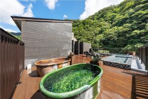a large green bath tub sitting on top of a deck at Hakkei in Maniwa