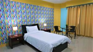 サラブリーにあるโรงแรมเมืองเพรียวอินน์ Mueang Phriao Inn Hotelのベッドルーム1室(ベッド1台、テーブル2台、椅子付)
