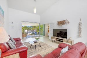 a living room with a red couch and a television at Verano Resort Noosa in Noosaville