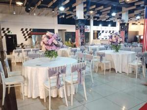 a room with tables and chairs with flowers on them at Hype Motorsport Hotel Nilai in Nilai