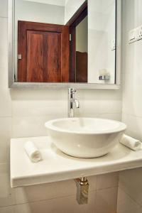 een badkamer met een witte wastafel en een spiegel bij Volunteer Ceylon in Ratnapura