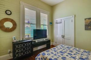 a bedroom with a bed and a flat screen tv at AbFab Seaside Cottage in Galveston