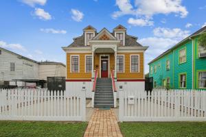 a yellow house with a white fence in front of it at AbFab Seaside Cottage in Galveston