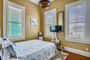 a bedroom with a bed and a tv and windows at AbFab Seaside Cottage in Galveston +21 photos