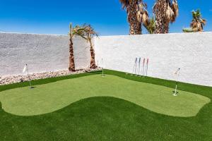 a putting green with palm trees and a white wall at Tropical Playhouse. Heated Pool . Spa . Golf . FUN in Lake Havasu City