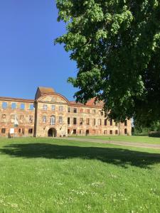 ein großes Backsteingebäude mit einem großen Grasfeld in der Unterkunft Ferienhaus am Klosterwald in Dargun