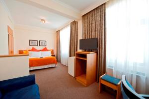 a hotel room with a bed and a tv at Hotel Thuringerhof in Windhoek