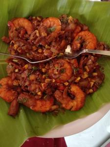 a plate of food with shrimp on a green leaf at The Little Prince - Mangalore Beach Homestay in Mangalore