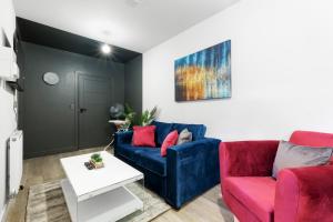 uma sala de estar com um sofá azul e cadeiras vermelhas em Infra Mews, Superb Delightful Apartments Perfect for Contractors & Long Stays, 1, 2 & 4 Bedroom, WiFi & Parking em Milton Keynes