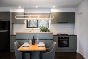 a kitchen with a wooden table and chairs and a kitchen with a stove at Little Jem in Daylesford