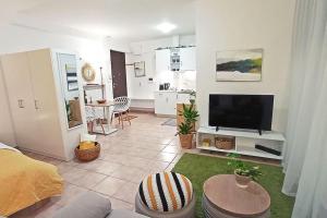 ein Wohnzimmer mit einem Sofa und einem TV in der Unterkunft Relaxing Studio Apt, 1 min to Highway, Parking in Athen
