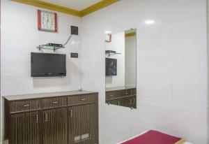 a living room with a tv on a white wall at RELAX GUEST HOUSE in Mumbai