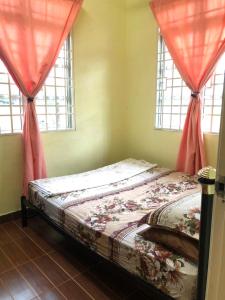 uma cama num quarto com duas janelas em Homestay Seri Hampar, Pendang em Pendang