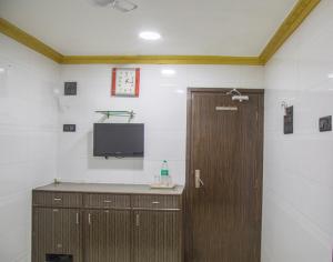 Habitación con puerta y TV en la pared en RELAX GUEST HOUSE en Bombay