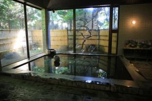 een zwembad met water in een kamer met ramen bij Seirakuen in Atsugi