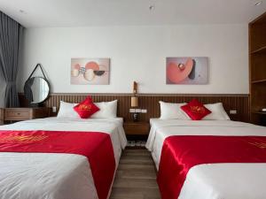 2 bedden in een hotelkamer met rode en witte lakens bij Amorii Hotel in Phu Quoc