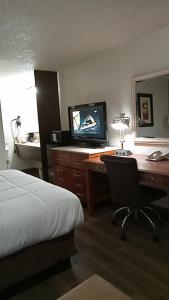 a hotel room with a bed and a desk with a television at SilverStone Lite in Sunnyside