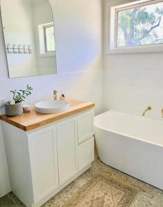 a bathroom with a sink and a tub and a mirror at COD & C0 Tocumwal in Tocumwal