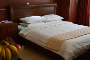 a bed with white sheets and a bunch of bananas at Norfolk Towers Serviced Apartment -Nairobi, City Centre CBD in Nairobi