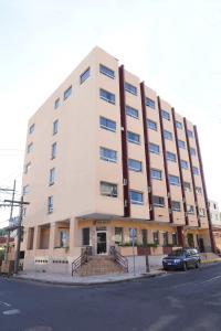 a large white building with a car parked in front of it at Hotel Palace Ejecutivo in San Pedro Sula