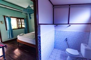 a bathroom with a toilet and a bed in a room at Lao Long Riverside and Budget Garden Guesthouse in Ban Khon