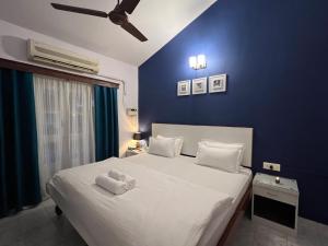 a bedroom with a large white bed with a blue wall at Villa By The Beach Goa in Benaulim +287 photos