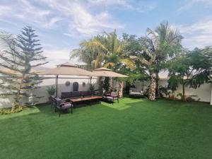 a lawn with a table and chairs and umbrellas at G R A N D C H A L E T in Salalah