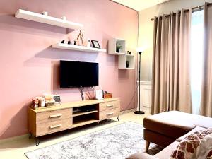 sala de estar con TV en una pared rosa en Apartment in Ladang Tok Pelam, en Kuala Terengganu