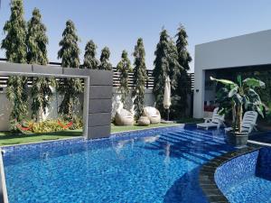 a swimming pool in front of a house with trees at G R A N D C H A L E T in Salalah