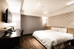 Habitación de hotel con cama y escritorio en Global Traveler Hotel en Kaohsiung