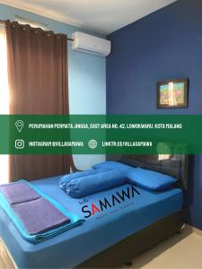 uma cama num quarto com uma parede azul em Villa Samawa em Malang