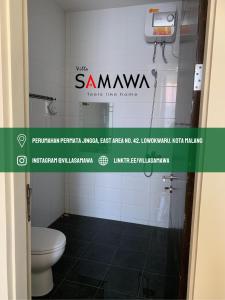 a bathroom with a toilet and a sign on the wall at Villa Samawa in Malang