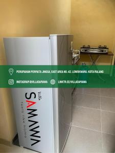 um frigorífico branco com uma placa num quarto em Villa Samawa em Malang