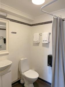 a white bathroom with a toilet and a sink at Säters Stadshotell in Säter +31 photos