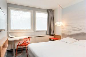 1 dormitorio con cama, escritorio y ventana en ibis Styles Paris Velizy, en Vélizy-Villacoublay