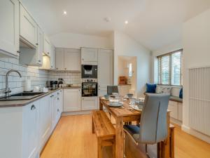 a kitchen with white cabinets and a wooden table at The Cottage in Langsett