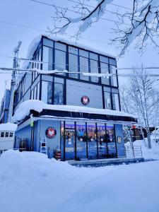 un edificio con nieve en el suelo delante de él en Q FOX BLACK DIAMOND HOTEL en Niseko