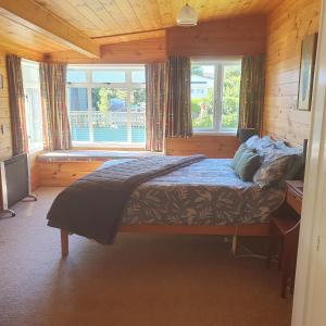 een slaapkamer met een bed voor een raam bij Daydream house, Sunrise, sunset views across lake in Rotorua