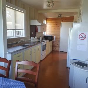 a kitchen with a white refrigerator and a sink at Daydream house, Sunrise, sunset views across lake in Rotorua